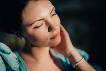 Portrait of young rural elegant woman posing on nature background. Sexy languid lady touching hair, enjoying summertime, sun rays. Vintage styled dress.