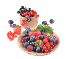 Assortment of fresh blueberries, raspberries, strawberries and black currants, in a wooden bowl, on an isolated white background