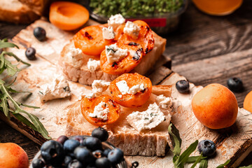 Healthy summer appetizer or snack Toast with soft dor blue cheese, fresh juicy peach, blueberry and honey snack, top view