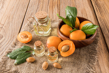 wooden bowl with glass bottles with cork lid apricot oil for face and body care. natural, organic product of cosmetics. rustic background.