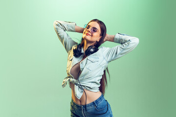 Portrait of young girl in casual clothes posing isolated over green studio background. Looks happy and delightful