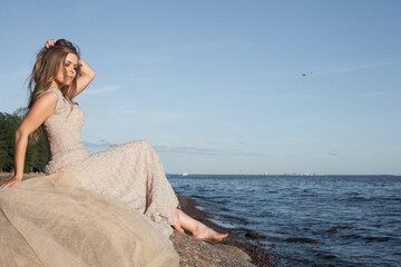 Fototapeta na wymiar Lovely woman in a beige dress on the sea coast