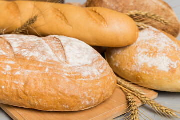 Freshly baked bread on cutting board against white wooden background. perspective view bread with copy space