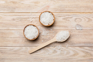 Obraz na płótnie Canvas A wooden bowl of salt crystals on a wooden background. Salt in rustic bowls, top view with copy space
