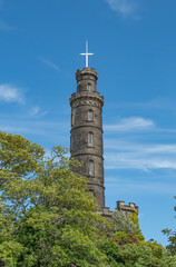 Fototapeta premium Church or cathedral tower or spire behind lush green trees on a bright and sunny day