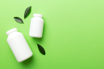 supplement pills with medicine bottle health care and medical top view. Vitamin tablets. Top view mockup bottle for pills and vitamins with green leaves, natural organic bio supplement, copy space