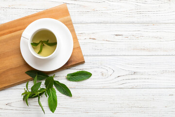 Cup of mint tea on table background. Green tea with fresh mint top view with copy space