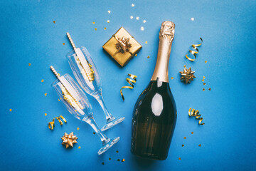 Bottle of champagne with colored glitter, confetti and gift box space for text on colorfull background, top view. Hilarious, christmas and birthday celebration © sosiukin