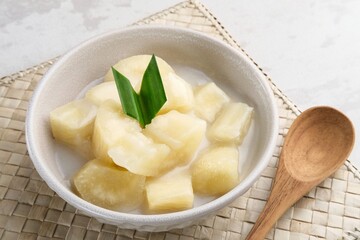 Singkong thailand, sweet cassava, made of boiled cassava, sugar and coconut milk. Served in bowl and pandan leaf.
