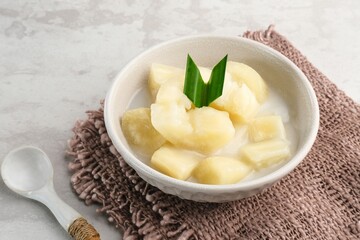 Singkong thailand, sweet cassava, made of boiled cassava, sugar and coconut milk. Served in bowl and pandan leaf.
