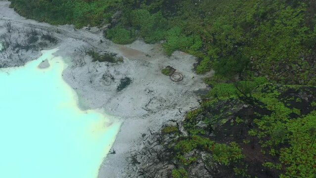 withered trees on a beach surrounded by a blue sulfur lake in Kawah Putih in Bandung Indonesia, aerial