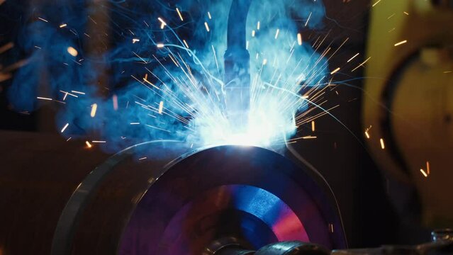 modern automated machine tool welds metal pipe with bright sparks and smoke in production plant shop. robotic welding machine. 4k.
