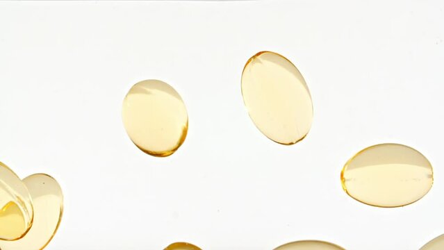 Capsule pills, Omega 3 gold oil capsules. Macro shot of Pills falling down in water and air bubbles on white background. The medicine concept, health care, treatment. Slow motion. High quality FullHD