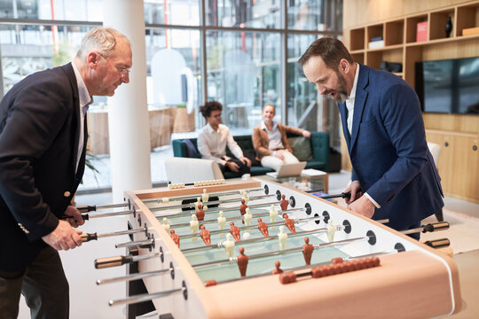 Zwei Gesch&auml;ftsleute spielen Tischfu&szlig;ball am Kickertisch