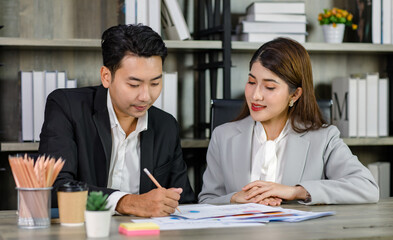 Asian young professional businesswoman secretary sitting smiling working showing graph chart paperwork document report to successful businessman entrepreneur in formal suit drinking coffee from cup