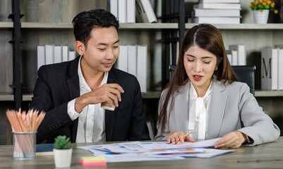 Asian young professional businesswoman secretary sitting smiling working showing graph chart paperwork document report to successful businessman entrepreneur in formal suit drinking coffee from cup