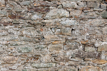 Natural ancient stone fence. Grunge stone wall granite background texture. Part of an old vintage castle stone barrier.