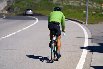 Fototapeta na wymiar Man on racing bicycle at summit of Gotthard Pass on a sunny summer day. Photo taken June 25th, 2022, Gotthard Pass, Switzerland.
