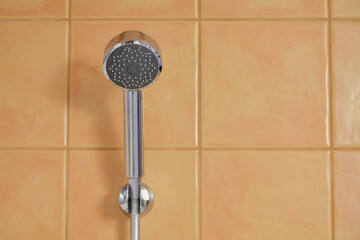 Steel shower head weighs on the wall close-up