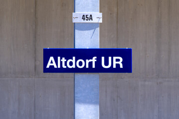 Sign at SBB railway station with concrete wall in the background at City of Altdorf, Canton Uri, on a sunny summer day. Photo taken June 25th, 2022, Altdorf, Switzerland.