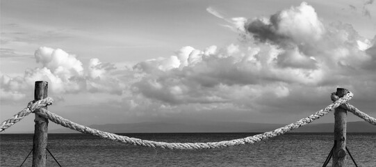 Black and white view on seafront and sky with sunlight clouds in evening - obrazy, fototapety, plakaty