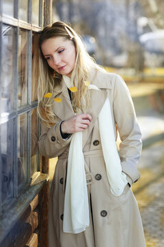young blond beautiful woman with long hair wearing trench coat closeup street portrait