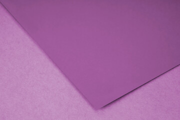 Plain purple paper sheet lying on pink textured Background like an open book from top angle	
