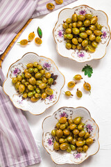 Three porcelain plate with yellow gooseberries, purple napkin on a white background. Healthy eating concept.