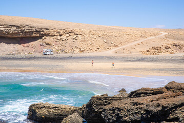 Fototapeta na wymiar Rear View of Two Friends Walking on the Beach to a Motorhome in Fuerteventura,Canary Island