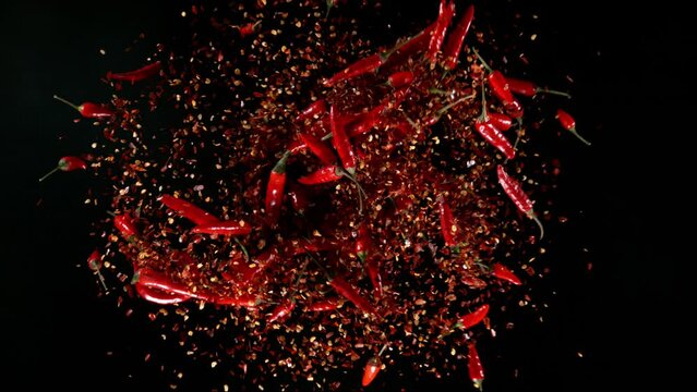 Super slow motion of exploding chilli peppers isolated on black. Overhead view, filmed on high speed cinema camera, 1000 fps. Ultimate perspective and concept of flying food.