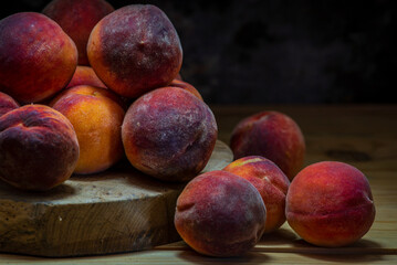 Group of fresh peaches on wood TABLE black background DARK MOOD,  ripe juicy organic  sweet fruit, vegan food, (Prunus persica) Close-Up, Harvest for food