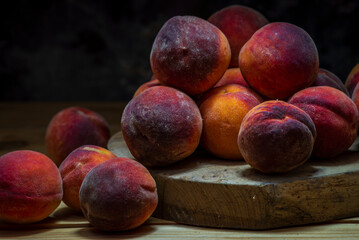 Group of fresh peaches on wood TABLE black background DARK MOOD,  ripe juicy organic  sweet fruit, vegan food, (Prunus persica) Close-Up, Harvest for food