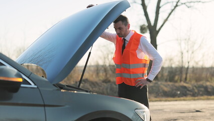 Disappointed man in formal outfit opening bonnet of broke down car to check engine. Sad businessman...