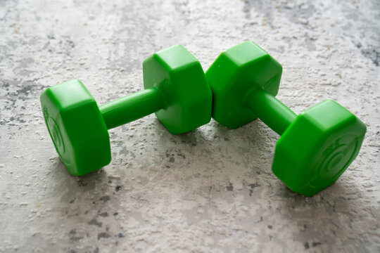 green dumbbells weight on a grey carpet floor background, concept of fitness sport healthy lifestyle 
