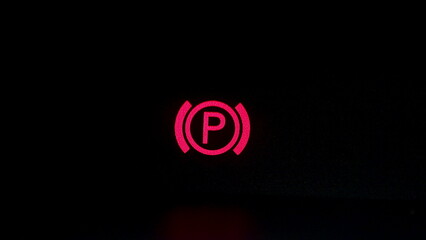 Parking brake control light in car dashboard. Close up of car's parking brake light coming on, on...