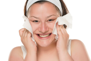 A young happy chubby woman removing makeup with the wet tissues  on white background