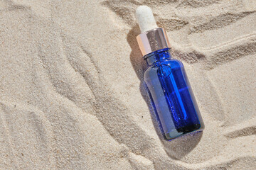 face serum of glass bottle with a pipette on a natural background with sand. Essential oil for moisturizing body skin. mockup of beauty fashion cosmetic bottle dropper product with skincare concept.