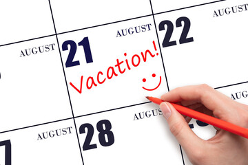 A hand writing a VACATION text and drawing a smiling face on a calendar date 21 August. Vacation...