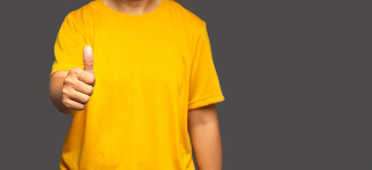 A close-up of the hand shows thumbs up while standing on gray background with copy space for text