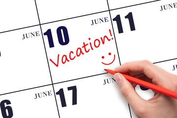 A hand writing a VACATION text and drawing a smiling face on a calendar date 10 June. Vacation...