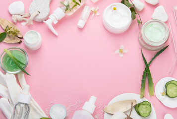 Face and body care products assortment on pink background.