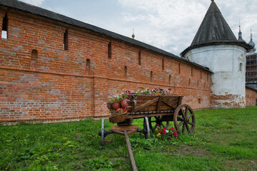 Old Wooden Cart filled with vases of flowers near the walls of the old fortress