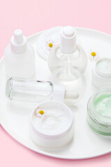 Face and body care products assortment on pink background.