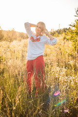 portrait of happy joyfull mature woman wearing traditional Ukrainian embroidered shirt - vyshyvanka in countryside during beautiful sunset