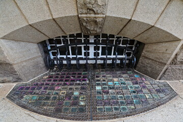 Arched basement window-decorative iron grillwork-colored glass pavement lights....
