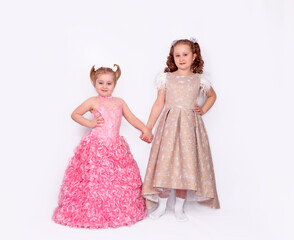 Fototapeta na wymiar A pair of adorable little girls in ball gowns isolated on a white background. Full-length image