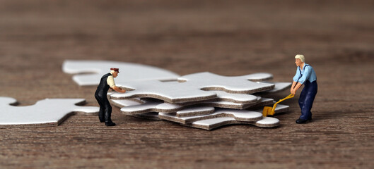 White puzzle pieces and miniature people with business concept. 
