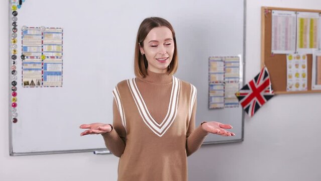 Front view of female english teacher talking and gesturing on camera while conducting lesson during video call. Distance studying, education and foreign language concept.