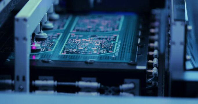 Circuit boards microchips in automatic equipment machine on conveyor line with blue light. Process of manufactoring of electronic microcircuits chips. High-tech technologies concept.