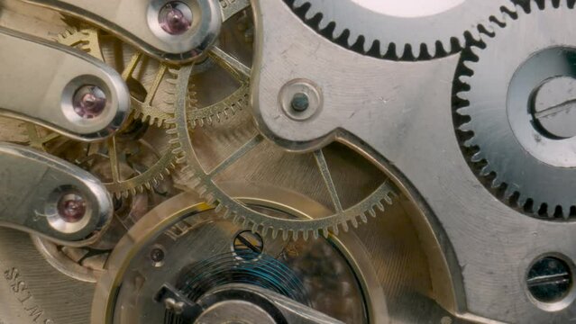 Internal clockwork mechanism macro. Rotating gold gears, metal gearing, wheels with tootheds. Disassembled watch with screws, cogwheels and winding spring. Old vintage clockwork working.